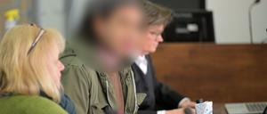 Die angeklagte Frau sitzt neben einer Dolmetscherin und ihrer Verteidigung in einem Verhandlungssaal in einem Landgericht. 