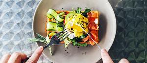 Eating brunch with waffle, avocado, cucumber, salmon and poached egg, personal perspective