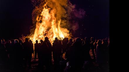 Besucher schauen sich das Branitzer Osterfeuer an. Die Kameraden der Freiwilligen Feuerwehr des Cottbuser Ortsteiles Branitz hatten bei den Einwohnern und Gewerbetreibenden etwa 25 Kubikmeter Holzabfall gesammelt und am Vormittag des heutigen Karsamstag zu einem Holzhaufen geschichtet. Zu dem Osterfeuer kamen mehrere Hundert Besucher. (zu dpa: «Osterfeuer wegen Trockenheit und Umwelt in der Diskussion») +++ dpa-Bildfunk +++