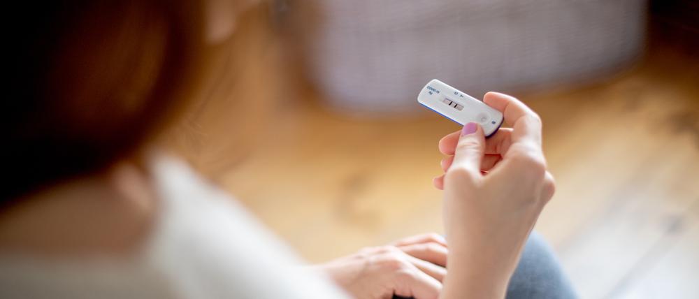 Eine Frau hält einen positiven Corona-Test in der Hand.
