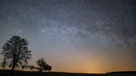 Der Sternenhimmel leuchtet in der Nacht über einer Landschaft. (Symbolbild)