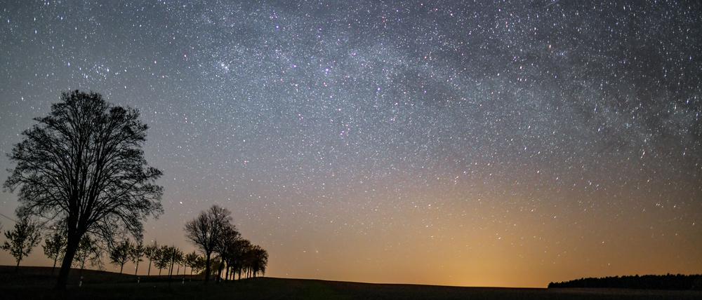 Der Sternenhimmel leuchtet in der Nacht über einer Landschaft. (Symbolbild)