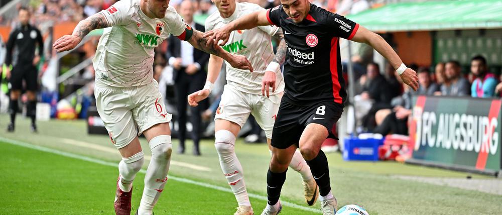 Viel Kampf in Augsburg: Frankfurts Farès Chaïbi (r) gegen FCA-Kapitän Jeffrey Gouweleeuw (l) und Kristijan Jakic.