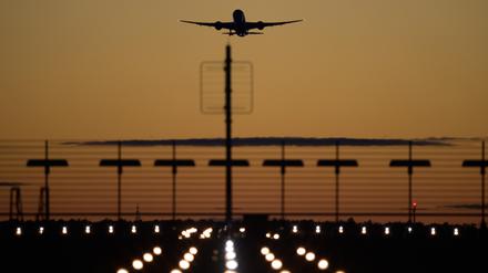 Ein Flugzeug startet vom Flughafen Berlin-Brandenburg (BER) in den roten Abendhimmel.