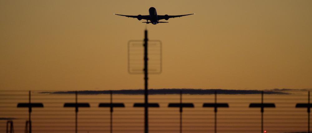 Ein Flugzeug startet vom Flughafen Berlin-Brandenburg (BER) in den roten Abendhimmel.