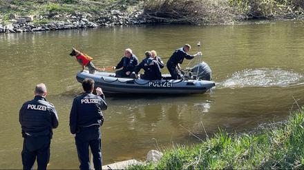 Polizisten suchen ein Gewässer ab.