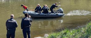 Polizisten suchen ein Gewässer ab.