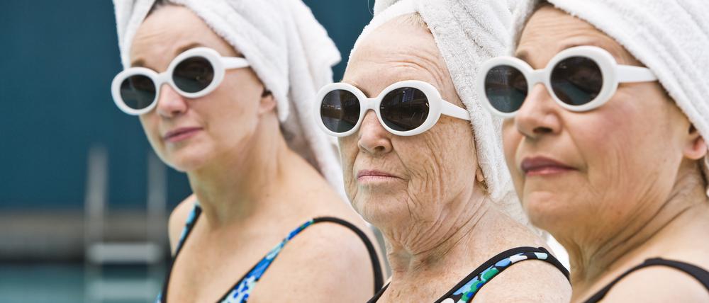 Gut abgesichert? Drei Damen im Ruhestands-Alter an einem Swimmingpool.