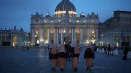 Gläubige gehen über den Petersplatz. Sie trauern um Papst Franziskus.