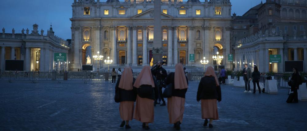 Gläubige gehen über den Petersplatz. Sie trauern um Papst Franziskus.