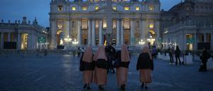 Gläubige gehen über den Petersplatz. Sie trauern um Papst Franziskus.