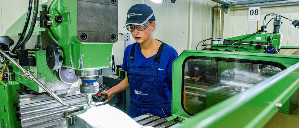 Eine Auszubildende der Berliner Wasserbetriebe bedient eine Fräsmaschine. 