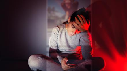 Eine 13-Jährige blickt in einem dunklen Raum auf ihr Smartphone. Über sie gelegt erscheint das Bild, das sie sich gerade ansieht.