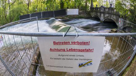 Ein Schild mit der Aufschrift Betreten verboten! Achtung Lebensgefahr! Hängt an einer Absperrung vor der künstlichen Welle am Eisbach.