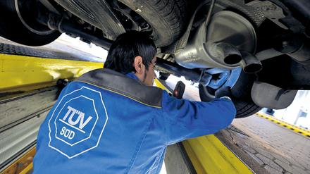 Ein Mitarbeiter des TÜV Süd kontrolliert am 09.06.2009 auf einem Prüfstand des TÜV in München (Bayern) den Unterboden und das Fahrwerk eines Autos. 