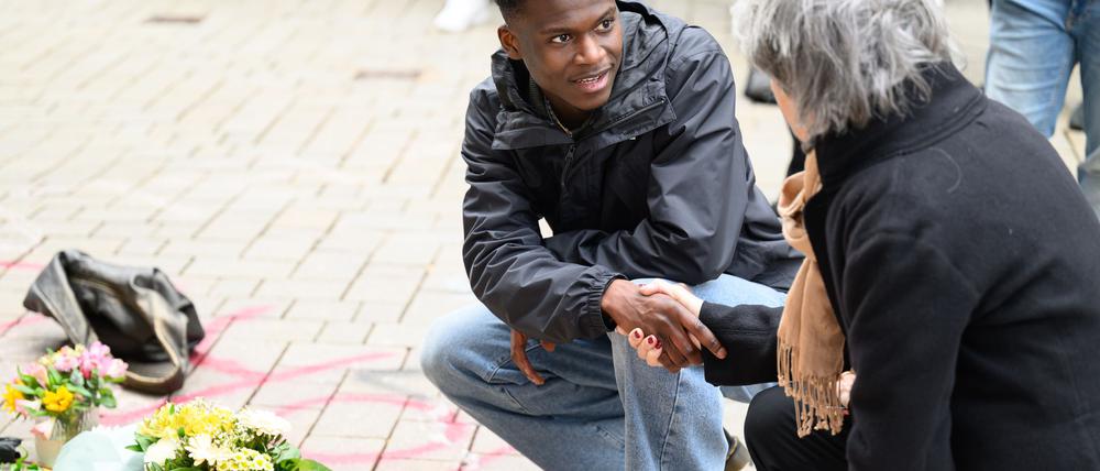 Suraj Mailitafi (l) von der Initiative „Gerechtigkeit für Lorenz“ spricht mit einer Passantin an dem Ort, an dem der 21-Jährige von der Polizei erschossen wurde.  