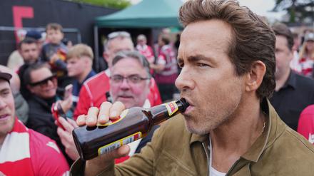 Schauspieler Ryan Reynolds lässt sich vor dem Spiel seines Clubs AFC Wrexham ein Bier schmecken.