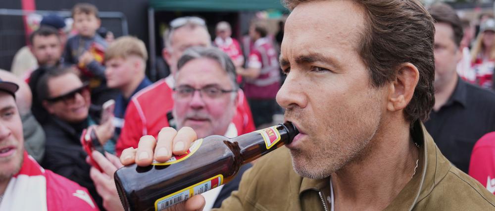 Schauspieler Ryan Reynolds lässt sich vor dem Spiel seines Clubs AFC Wrexham ein Bier schmecken.