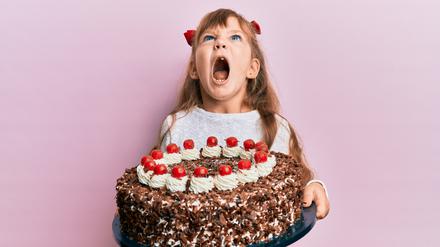 Ein Mädchen hat eine riesige Schwarzwälder-Kirschtorte in den Händen und schreit mit offenem Mund. (Symbolbild)