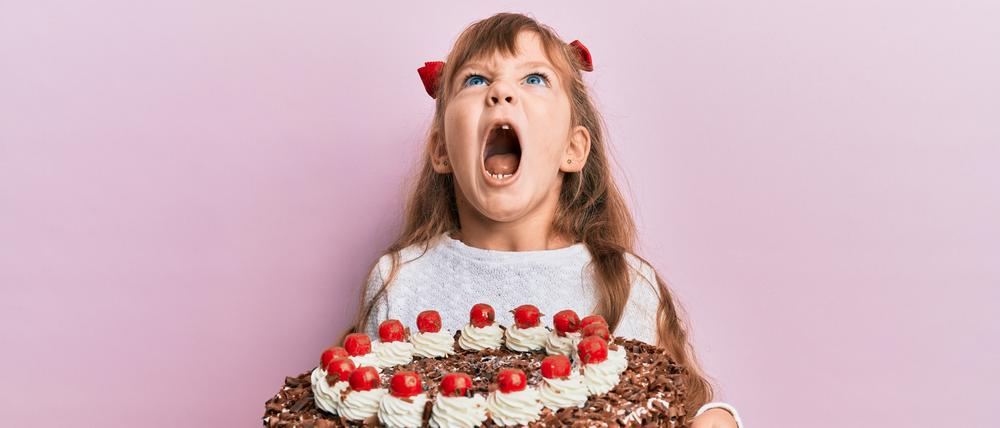 Ein Mädchen hat eine riesige Schwarzwälder-Kirschtorte in den Händen und schreit mit offenem Mund. (Symbolbild)