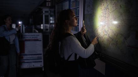 Eine Frau leuchtet mit der Taschenlampe ihres Handys einen Plan des Madrider U-Bahn-Netzes.