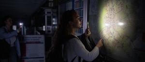 Eine Frau leuchtet mit der Taschenlampe ihres Handys einen Plan des Madrider U-Bahn-Netzes.