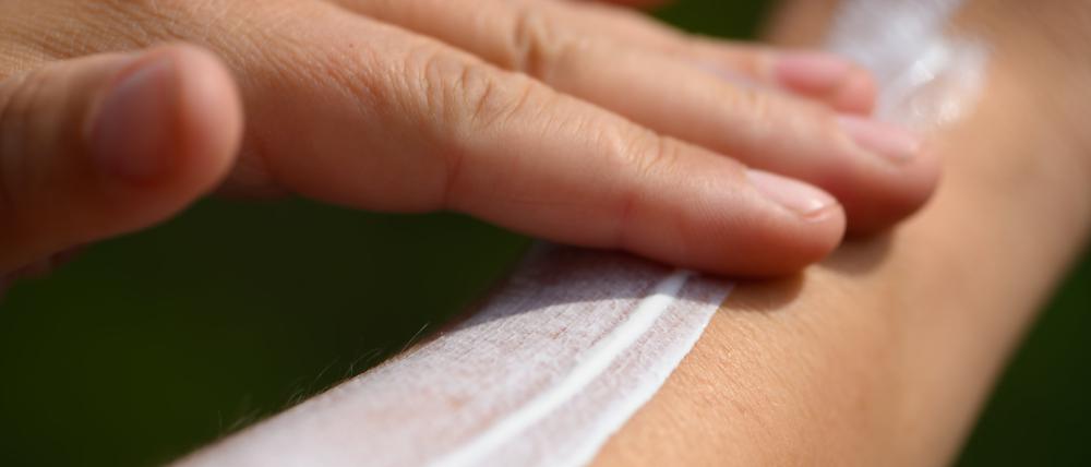 Eine Frau schmiert sich ihren Unterarm mit Sonnencreme ein.