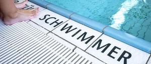 Eine Person steht am Beckenrand eines Schwimmbades.