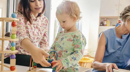 Ein Kleinkind zwischen Erzieherinnen im Kindergarten