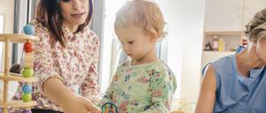 Ein Kleinkind zwischen Erzieherinnen im Kindergarten