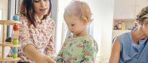 Ein Kleinkind zwischen Erzieherinnen im Kindergarten