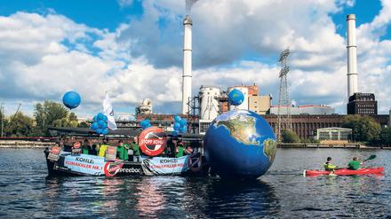 Ein Boot mit Transparenten zieht am 26.09.2015 in Berlin eine nachgebildete Weltkugel vor dem Kraftwerk Klingenberg (Symbolbild).
