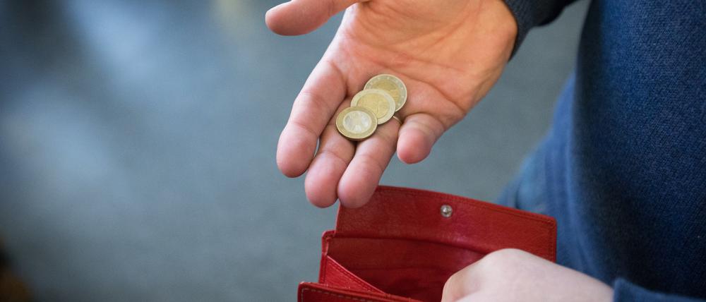 Münzen im Wert von fünf Euro werden in Paderborn über ein rotes Portemonnaie gehalten.  