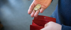 ARCHIV - 31.01.2017, Nordrhein-Westfalen, Paderborn: ILLUSTRATION - Münzen im Wert von fünf Euro werden in Paderborn über ein rotes Portemonnaie gehalten. (zu dpa: «Wohlfahrtsverband: Jeder Sechste in MV ist arm») Foto: Friso Gentsch/dpa +++ dpa-Bildfunk +++