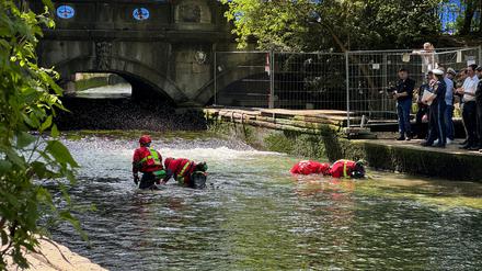 Polizeitaucher durchsuchen den Wellenbereich im bereits abgesenkten Eisbach.