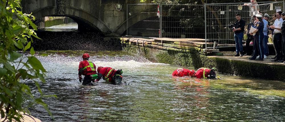 Polizeitaucher durchsuchen den Wellenbereich im bereits abgesenkten Eisbach.