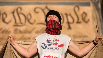 Syril, 25, carries a large banner of the U.S. constitution with a number of other demonstrators during a protest marking U.S. President Donald Trump's first 100 days in office, in Washington, D.C., U.S., April 30, 2025. REUTERS/Allison Bailey