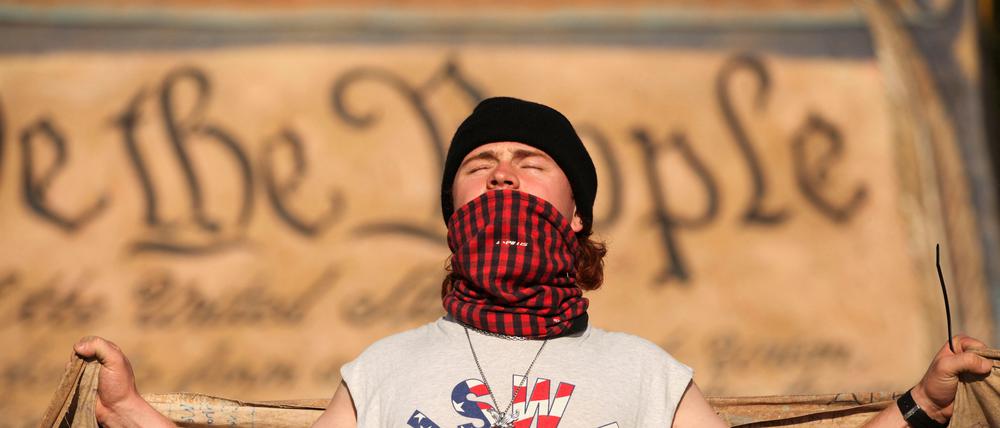 Syril, 25, carries a large banner of the U.S. constitution with a number of other demonstrators during a protest marking U.S. President Donald Trump's first 100 days in office, in Washington, D.C., U.S., April 30, 2025. REUTERS/Allison Bailey