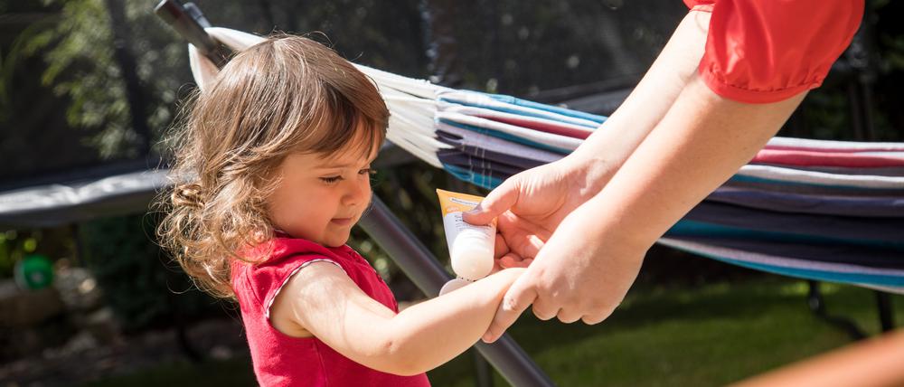 Ein Kind wird eingecremt. Kinderhaut ist gegenüber der Sonne besonders empfindlich.