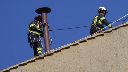 Feuerwehrleute platzieren den Schornstein auf dem Dach der Sixtinischen Kapelle, wo sich die Kardinäle zur Wahl des neuen Papstes versammeln werden.