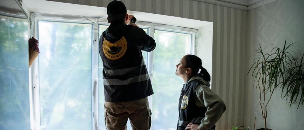 Plastikfolie wird als provisorischer Ersatz an Fenster angebracht, deren Scheiben bei dem Raketenangriff barsten.