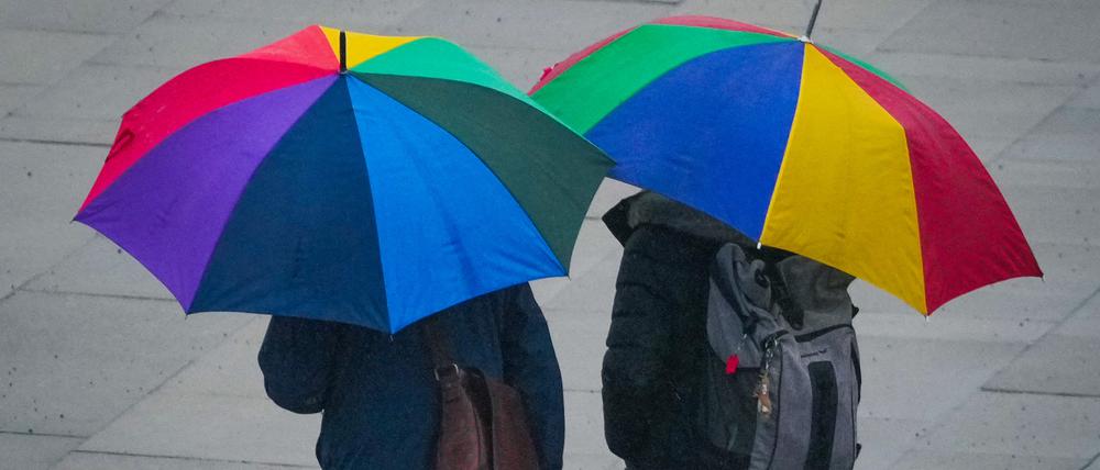 Passanten mit bunten Regenschirmen gehen bei leichtem Regen durch die Potsdamer Innenstadt.
