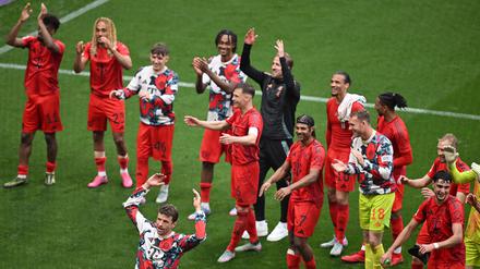 Thomas Müller (vorne) stimmte nach dem 3:3 in Leipzig die Welle mit den Fans an.
