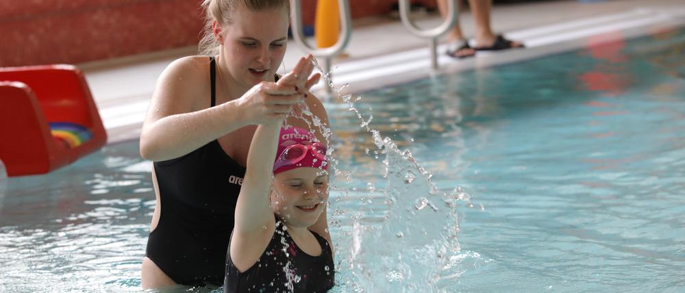 Eine Schwimmlehrerin bei einer Übung mit einem Mädchen.