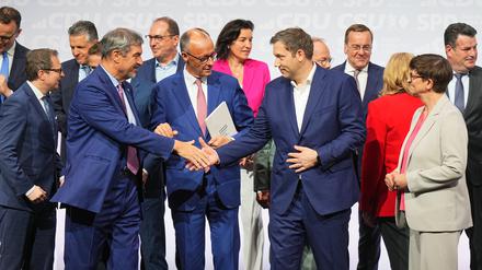 CDU-Vorsitzender und -Kanzlerkandidat Friedrich Merz (M), CSU-Vorsitzender Markus Söder (l) und SPD-Vorsitzender Lars Klingbeil, designierter Bundesfinanzminister und Vizekanzler, geben sich nach der Unterzeichnung des Koalitionsvertrags von CDU, CSU und SPD zur Bildung einer neuen Bundesregierung neben der SPD-Vorsitzenden Saskia Esken die Hand.