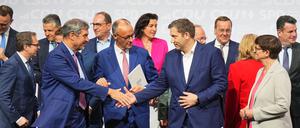 CDU-Vorsitzender und -Kanzlerkandidat Friedrich Merz (M), CSU-Vorsitzender Markus Söder (l) und SPD-Vorsitzender Lars Klingbeil, designierter Bundesfinanzminister und Vizekanzler, geben sich nach der Unterzeichnung des Koalitionsvertrags von CDU, CSU und SPD zur Bildung einer neuen Bundesregierung neben der SPD-Vorsitzenden Saskia Eskene im Euref-Campus die Hand. 