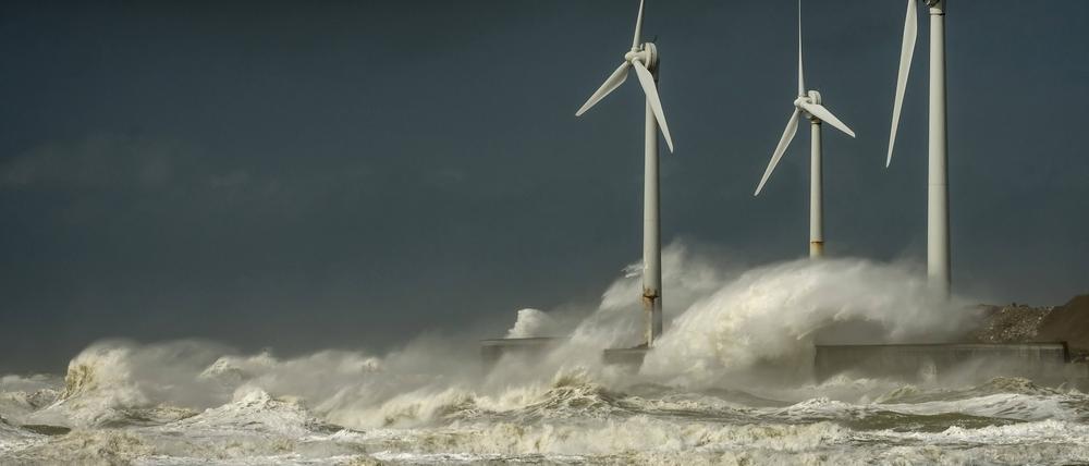 Sturmwellen treffen auf Windkraftanlagen.