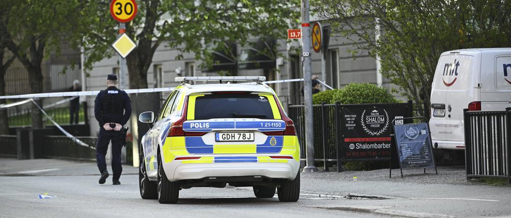 Ein Einsatzfahrzeug und ein Polizist stehen am Einsatzort nach Schüssen am Vaksala-Platz im Zentrum von Uppsala. Drei Menschen sind hier vor knapp zwei Wochen ermordet worden.