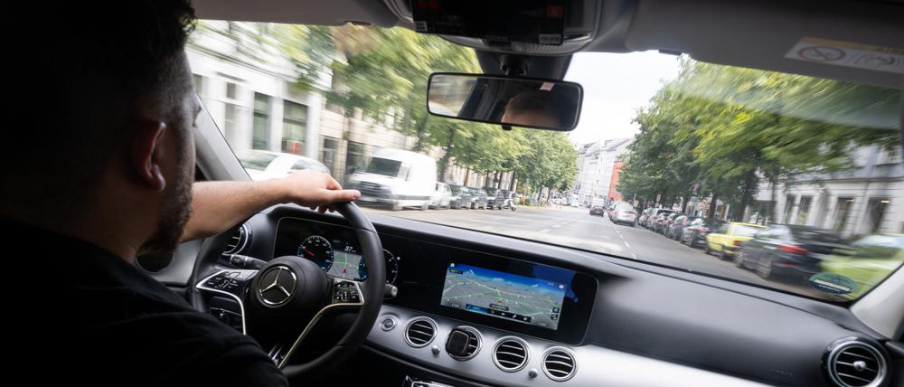 Ein Fahrer fährt in einem Taxi, das auch über Uber und Bolt gebucht werden kann.