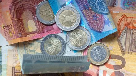 Euro-Münzen und Banknoten liegen aufeinander. (Symbolbild)